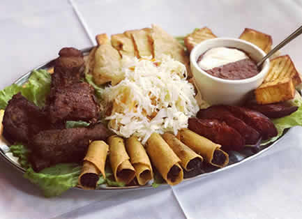 Platter of grilled meats, sausages, rolled fried tacos, slaw and toasted bread with a dipping sauce