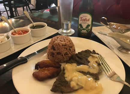 Plate of grilled steak with cream sauce, rice and beans and fried sweet plantains, with a Toña beer